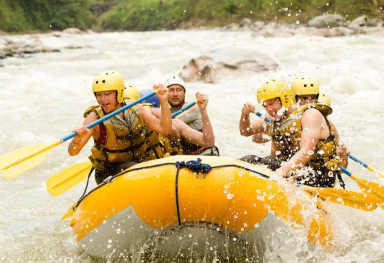 Group of people in a yellow dinghy white water rafting